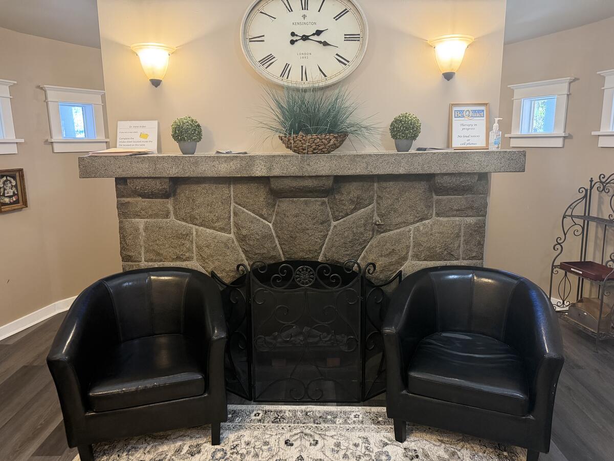 Original stone fireplace in the shared waiting area with leather chairs and warm lighting