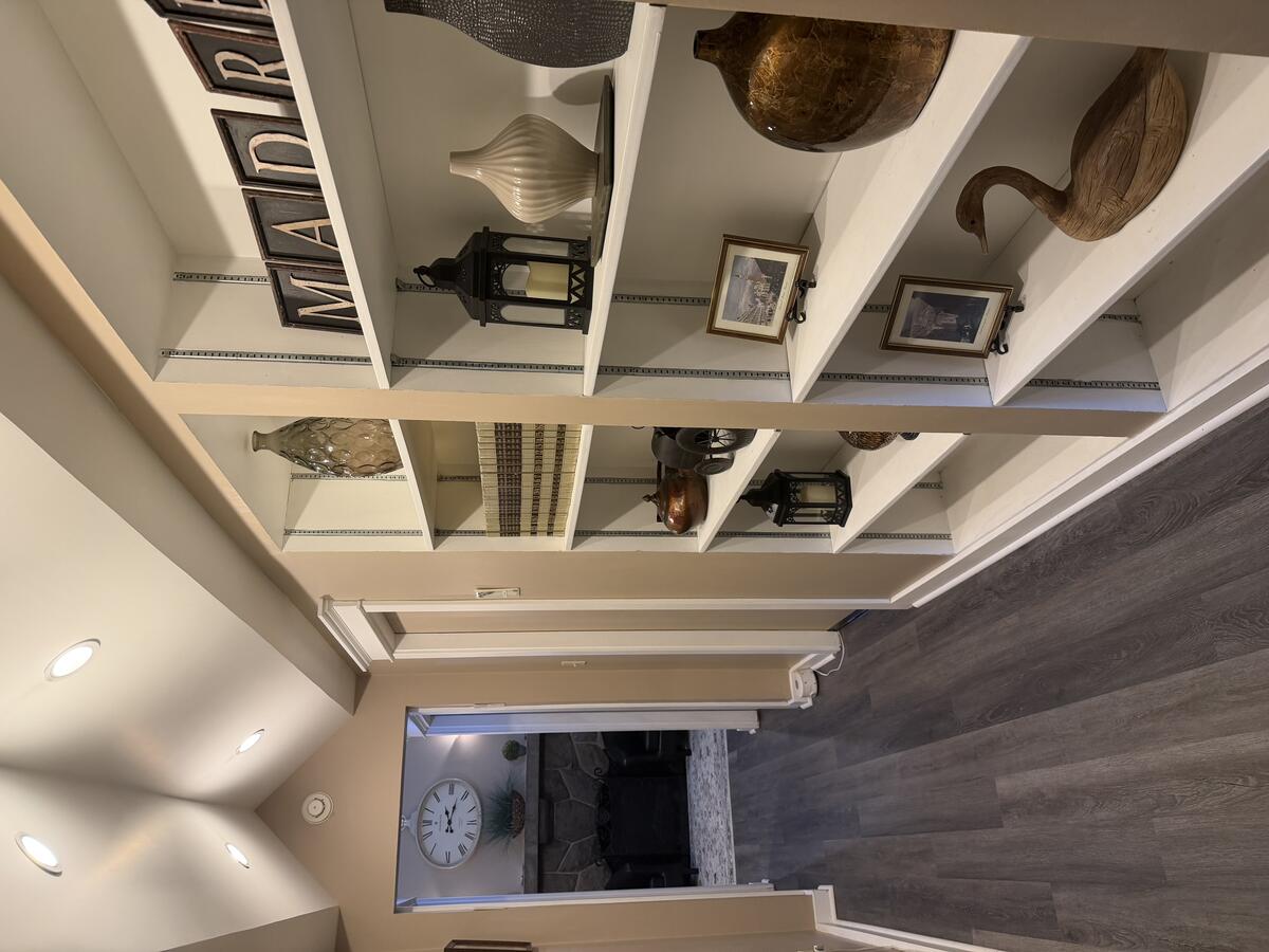 Interior hallway with built-in shelving, vaulted ceiling, curated objects, and original architectural details